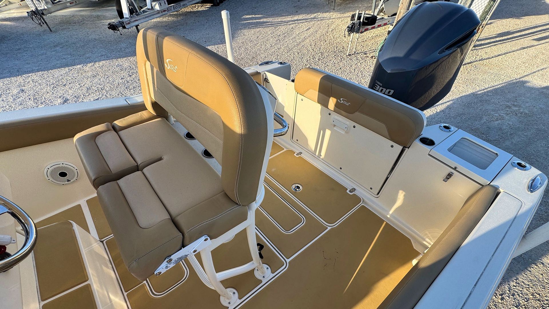 Tan boat deck with cushioned bench seats and a steering wheel in bright sunlight