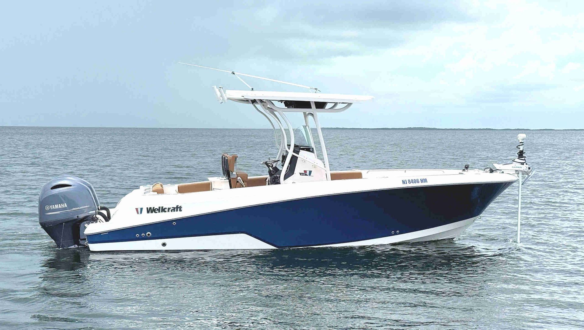 Wellcraft 242 Fisherman boat on calm water, side view with T-top canopy and outboard motor