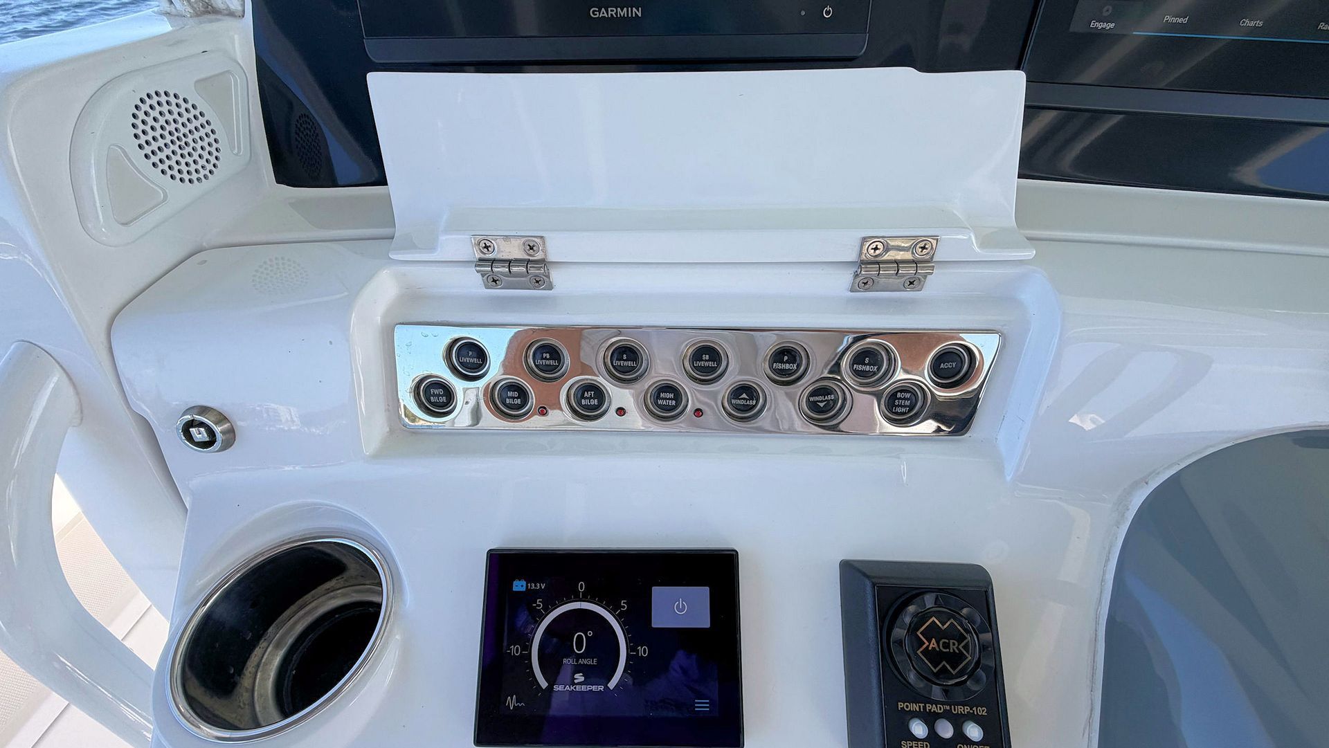Boat helm with white dashboard, steering wheel, control panel, and storage compartment open