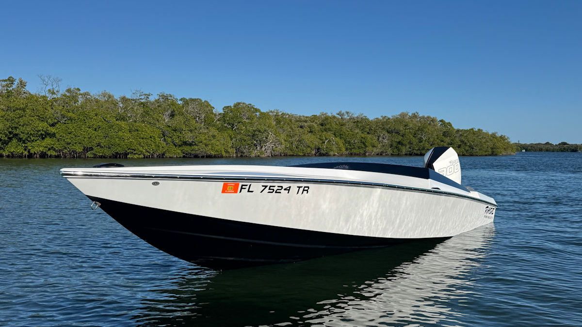 White and black speedboat on water, Florida mangroves in background, sunny day.