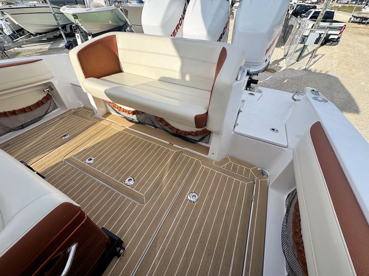 Boat interior with brown and white seating and flooring, three outboard motors.