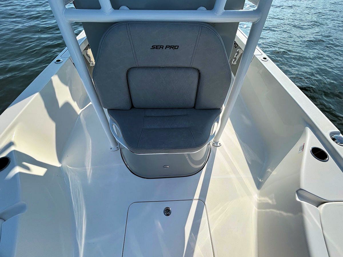 Inside of a Sea Pro boat, view from bow, grey cushioned seating, white boat.