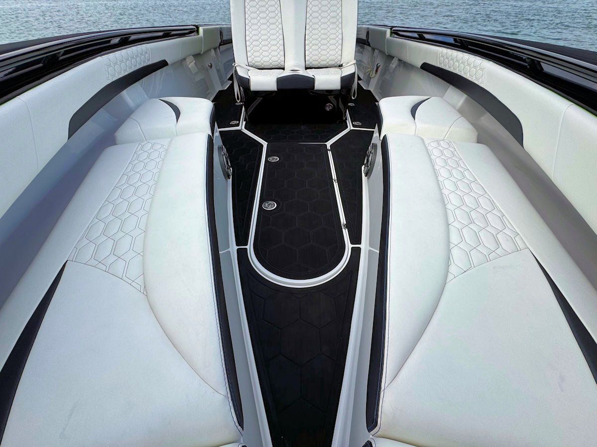 White and black interior of a speedboat, with two white seats, black flooring, and padded white sides.