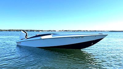 White and black speedboat on blue water under a clear sky.