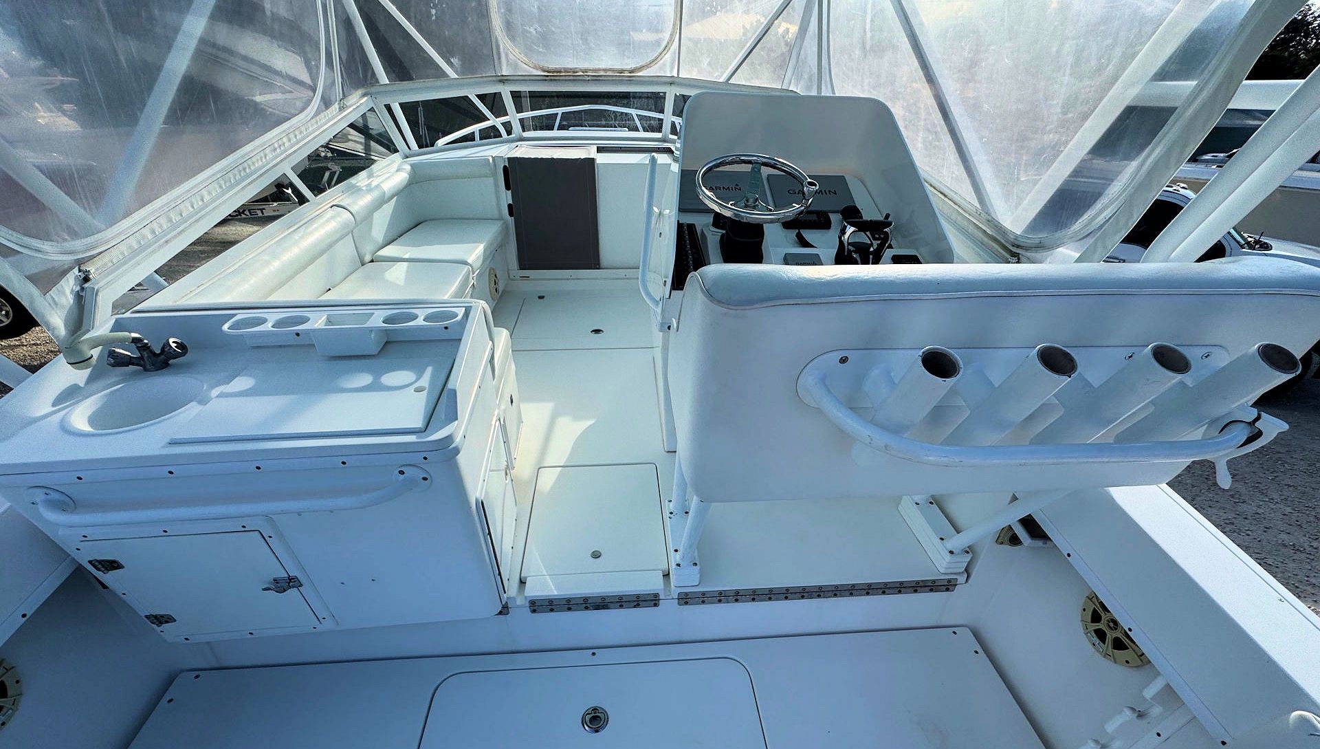Interior of a white boat cabin with open storage hatches and a clear plastic canopy overhead