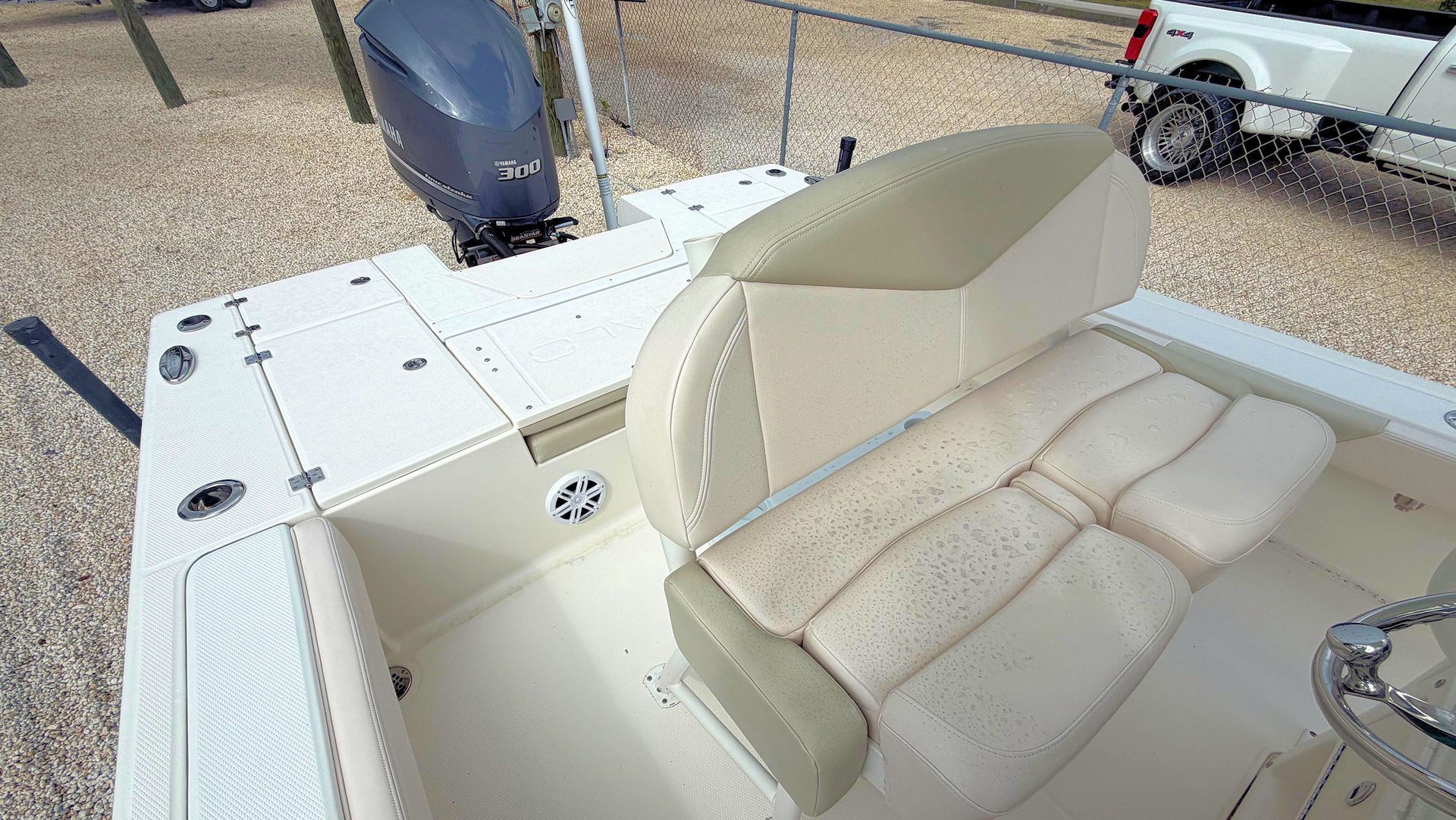 White interior of a boat with captains double seat with beige cushioned bench seats and a helm, viewed from above