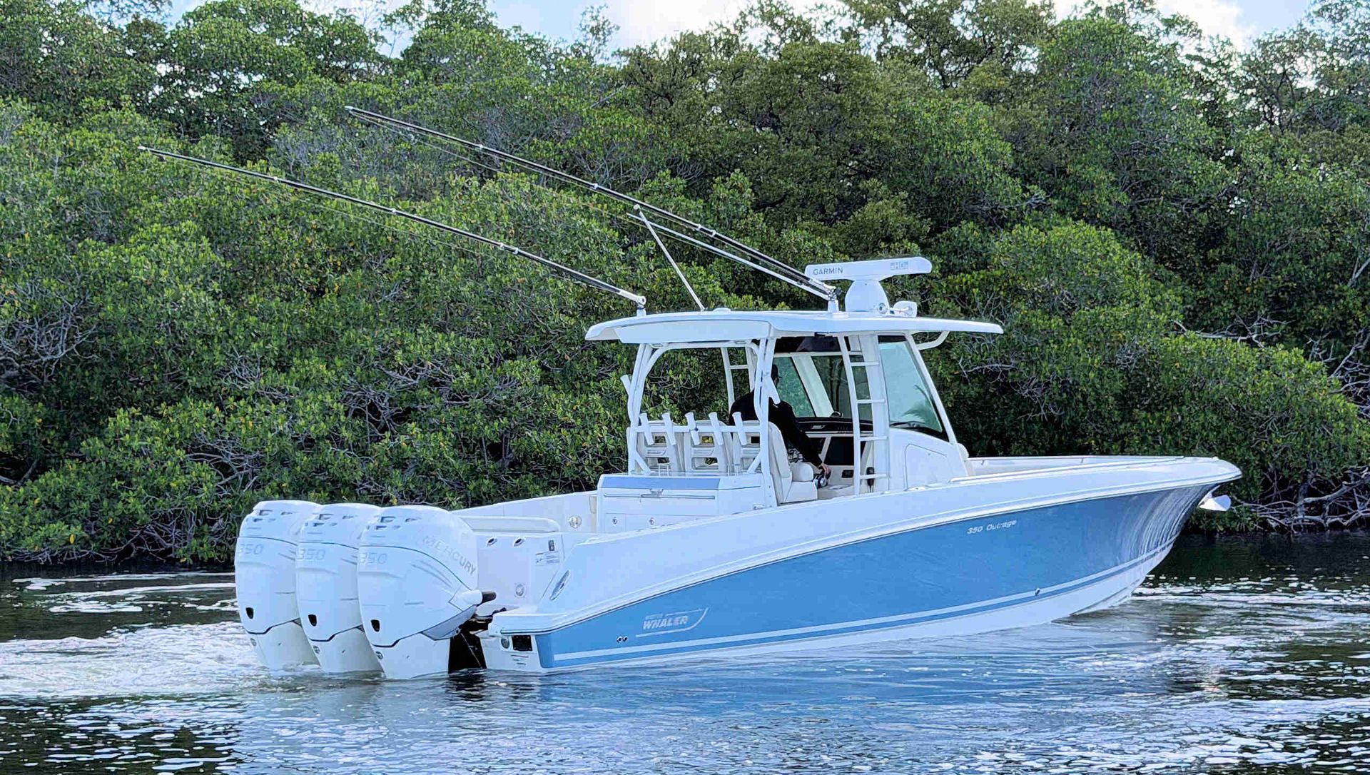 Blue and white center-console boat cruising on calm water beside green mangroves
