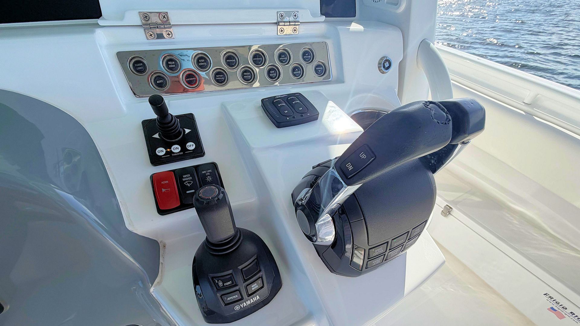 Boat helm with throttle, joystick controls, and instrument panel in a white cockpit