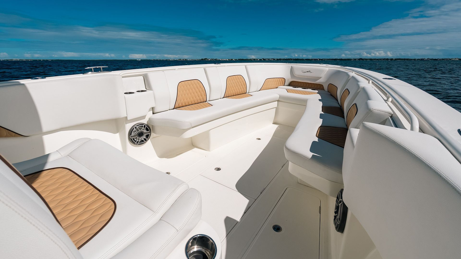 Luxurious white yacht bow seating with tan cushions on a calm blue ocean