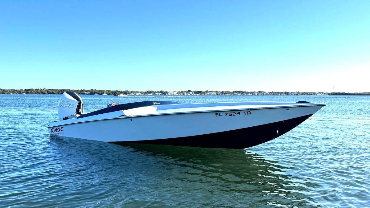 White and black motorboat on calm water, clear sky in background.