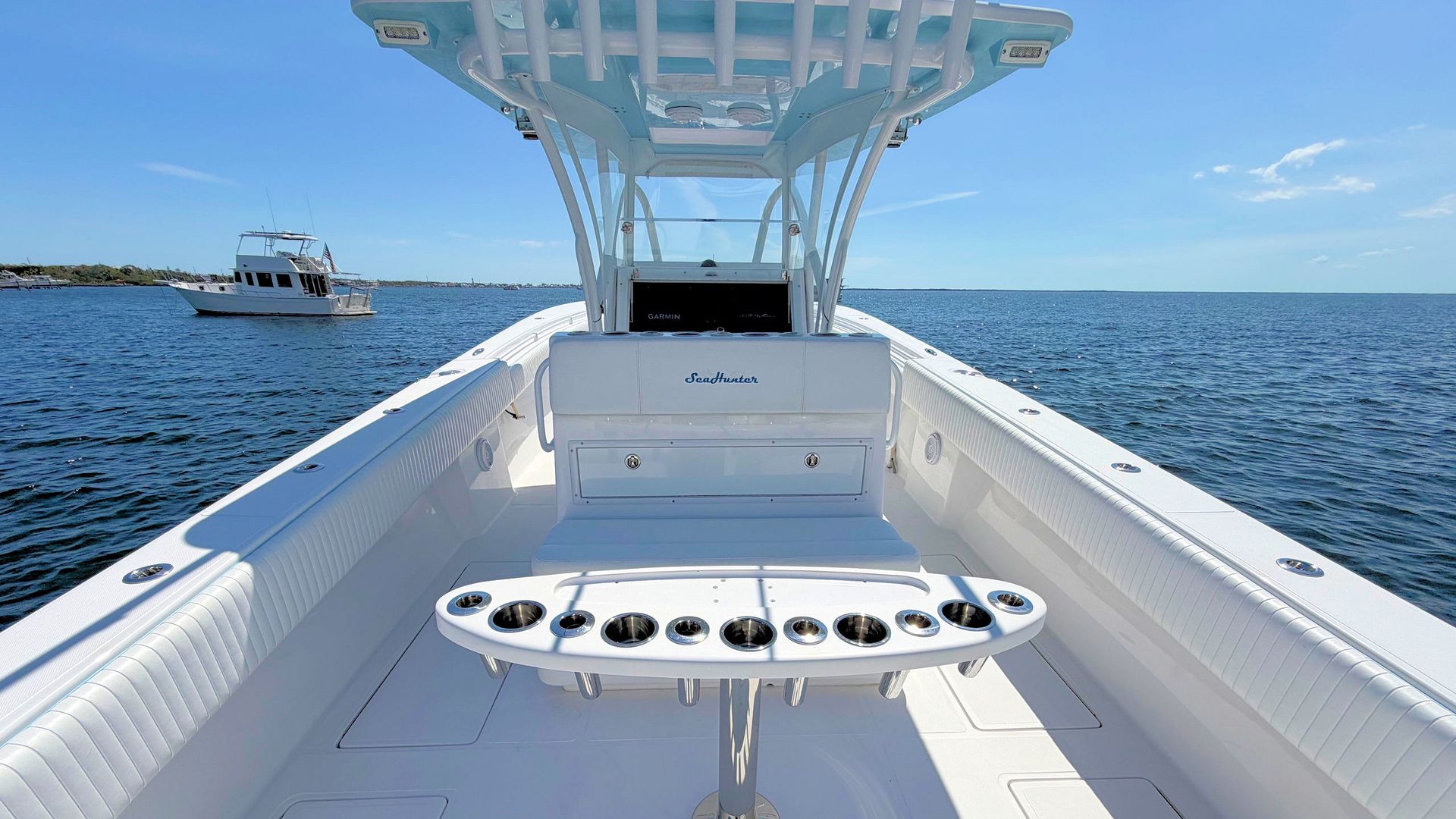 White interior  of a fishing boat deck with rod holders facing open blue ocean under a clear sky