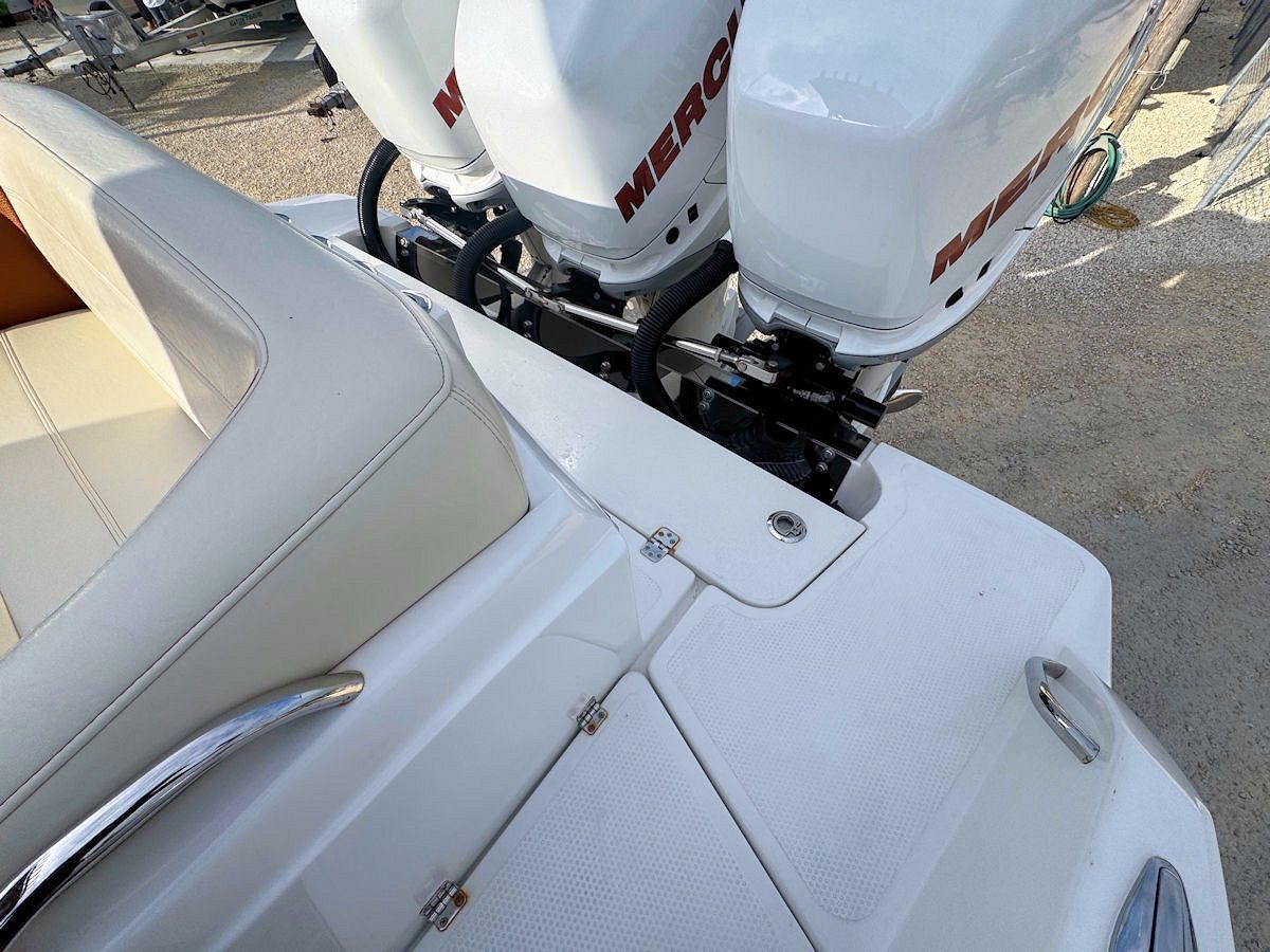White boat with triple Mercury outboard motors.