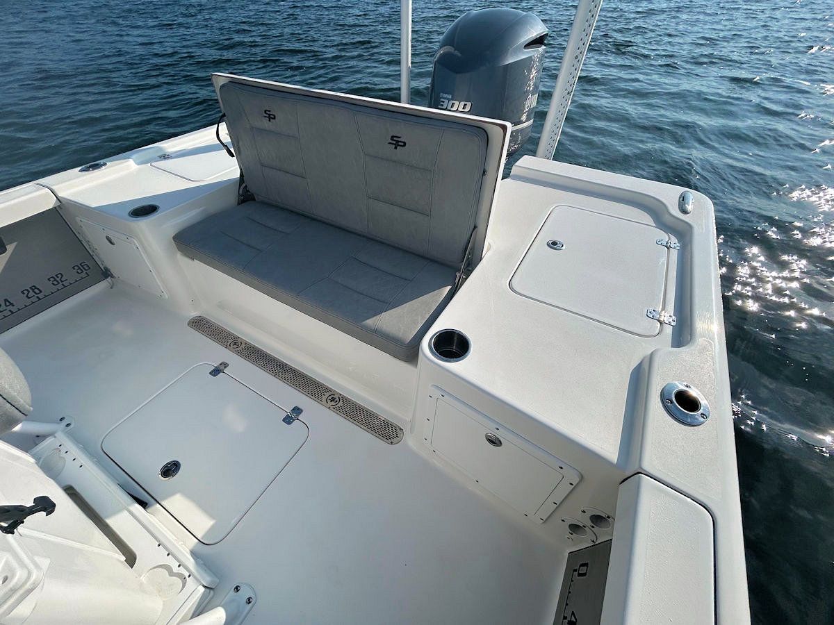White fishing boat interior with cushioned bench seat, storage compartments, and outboard motor.
