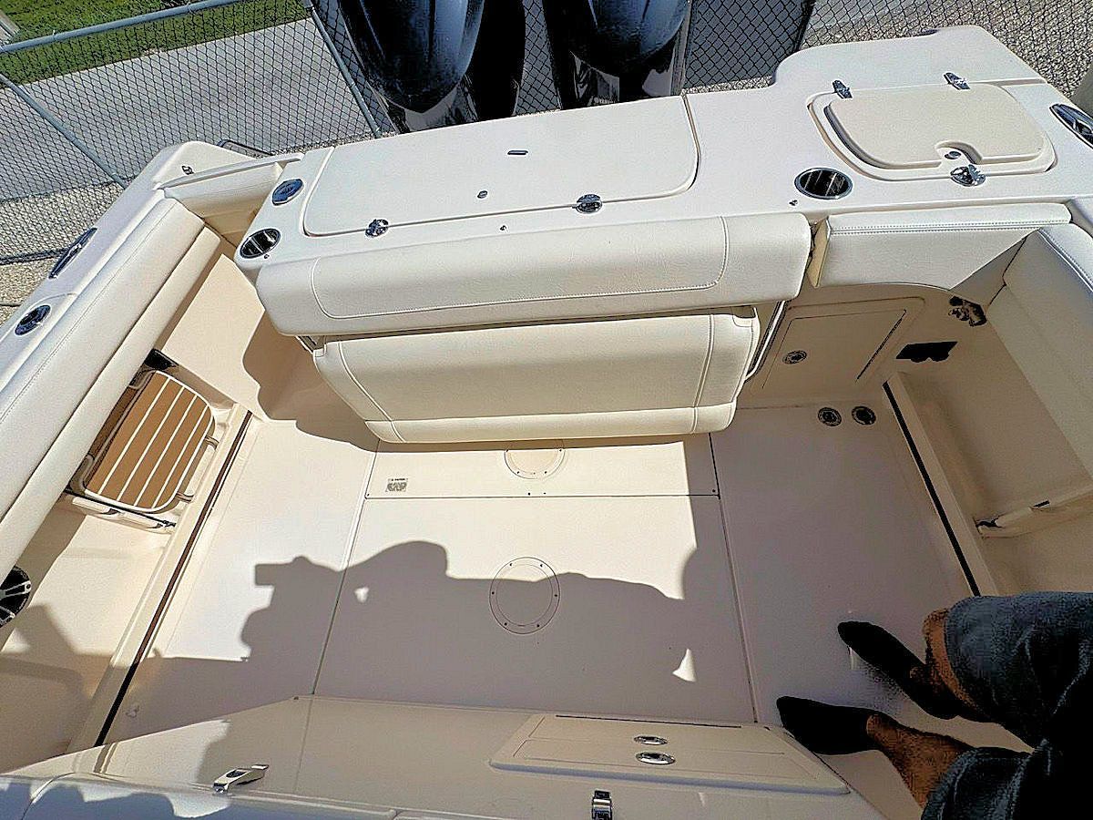 Inside of a beige and white boat with seats and deck, view from above.