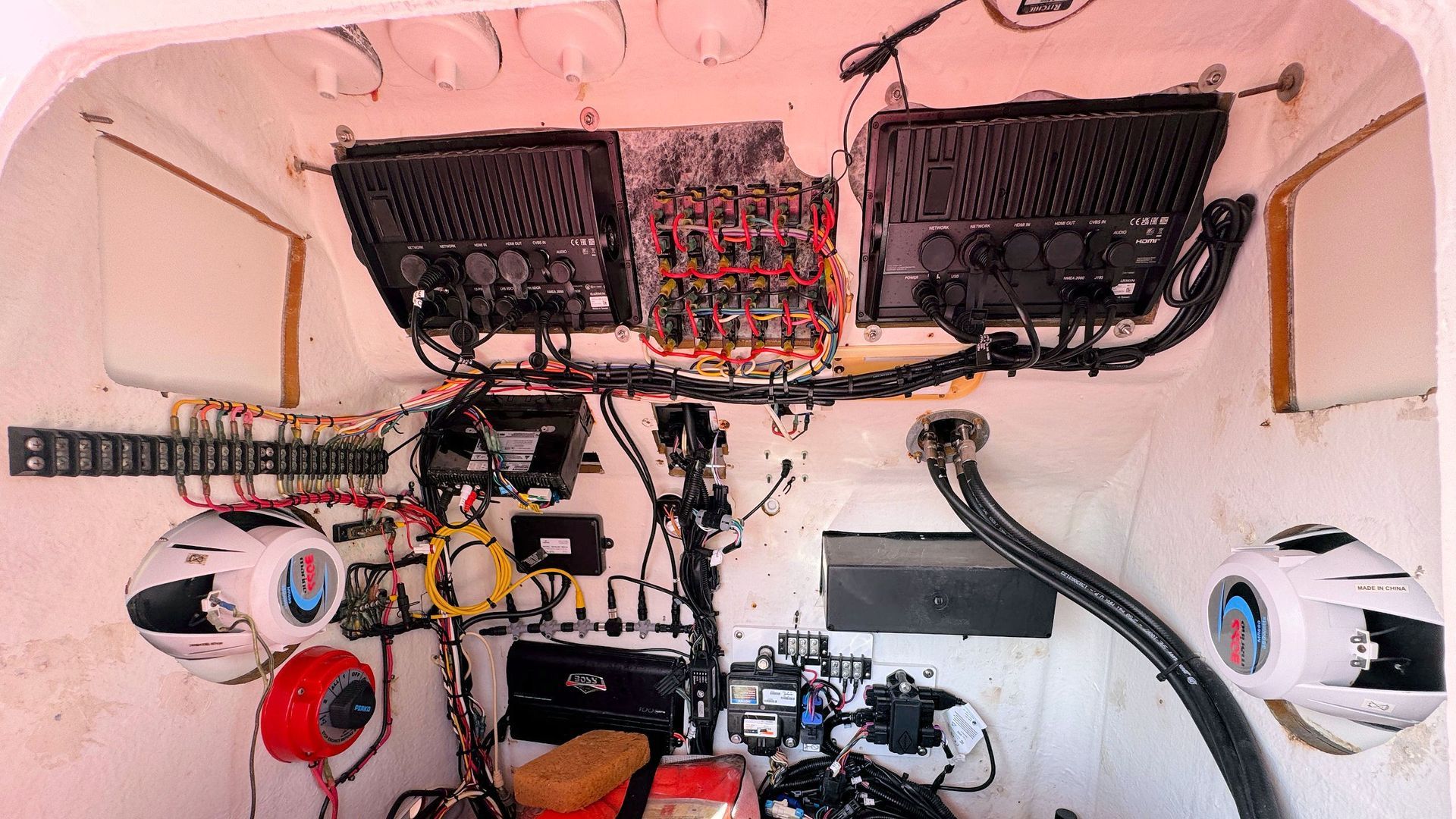 Interior of a small cockpit with exposed wiring, gauges, and panels in a white enclosure