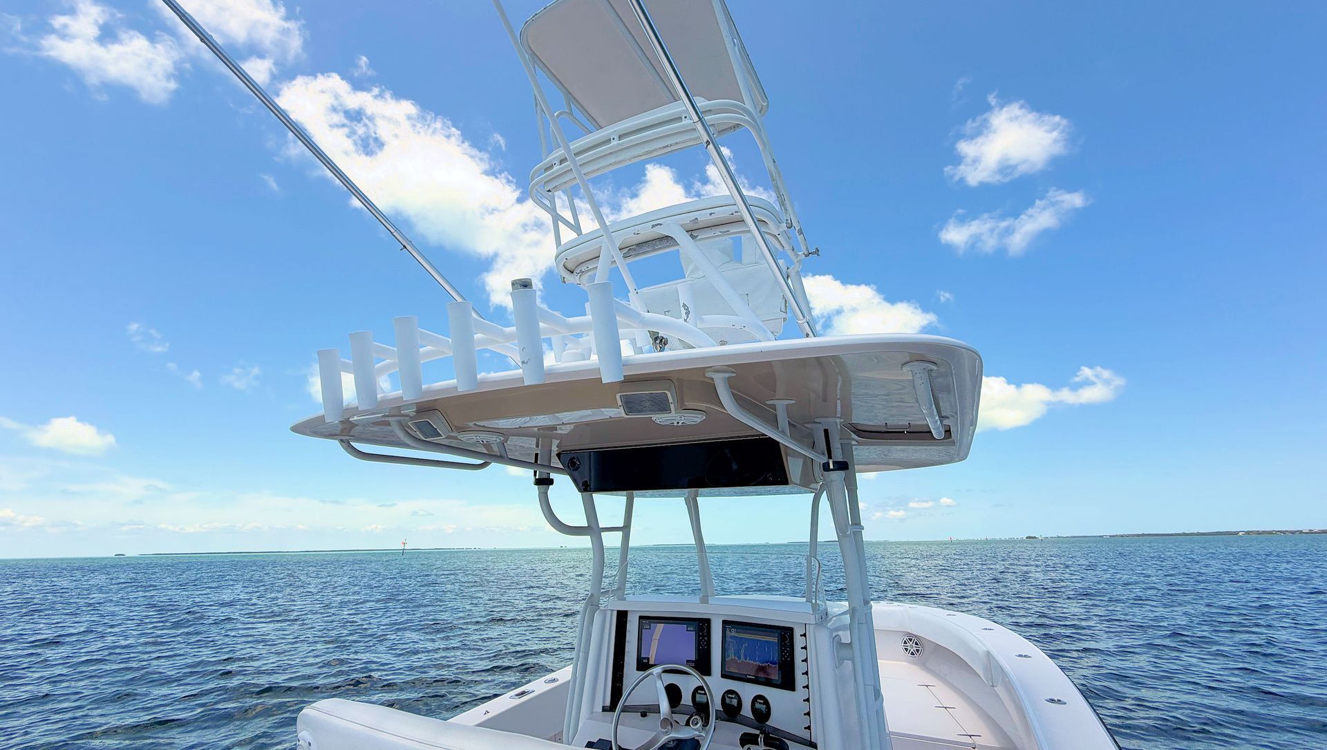 Fishing boat helm and t-top under blue sky with mounted radar and antennas on open water
