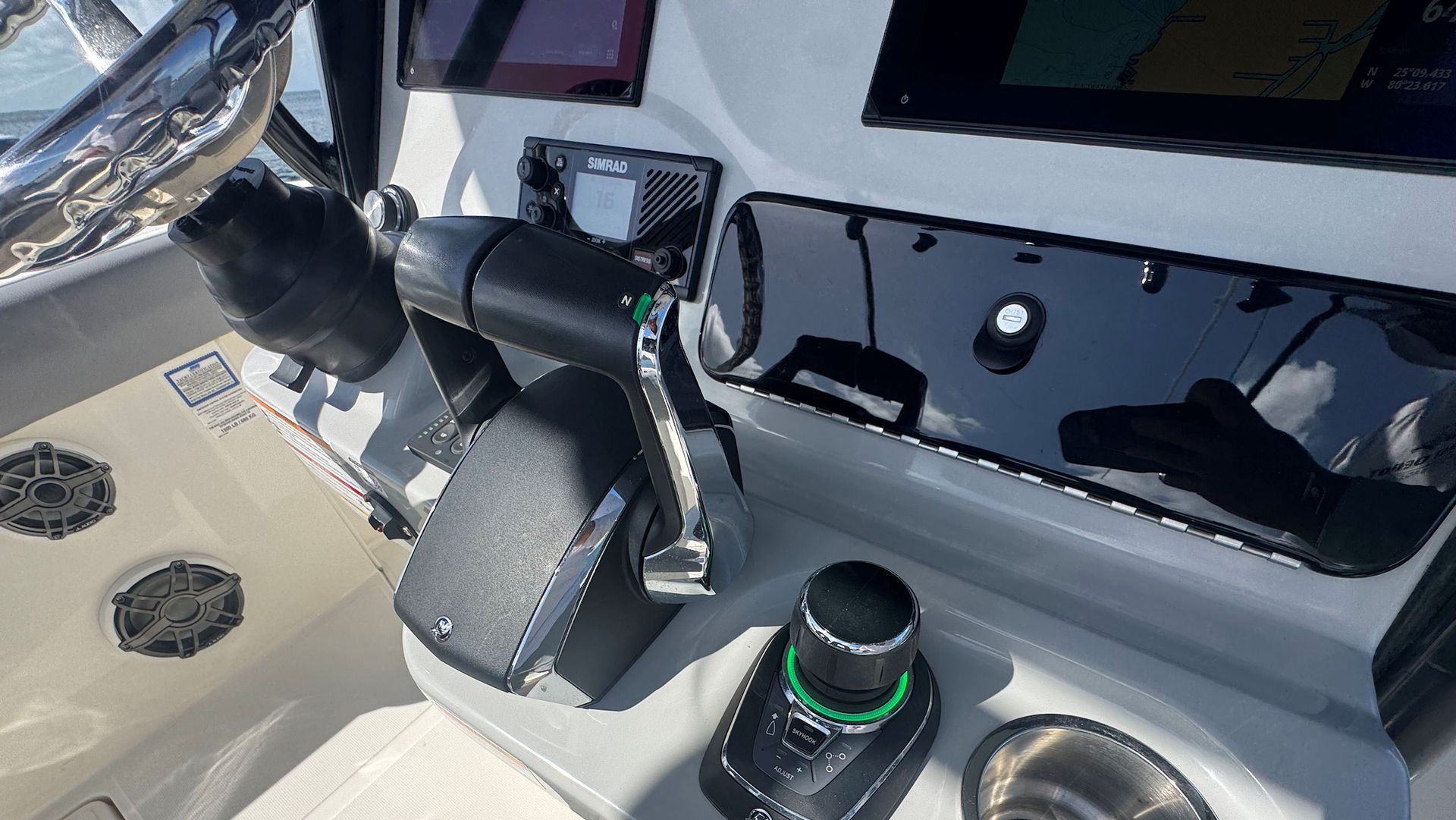 The helm of a boat featuring a dual-lever throttle, a joystick controller, and a dashboard with electronic displays.
