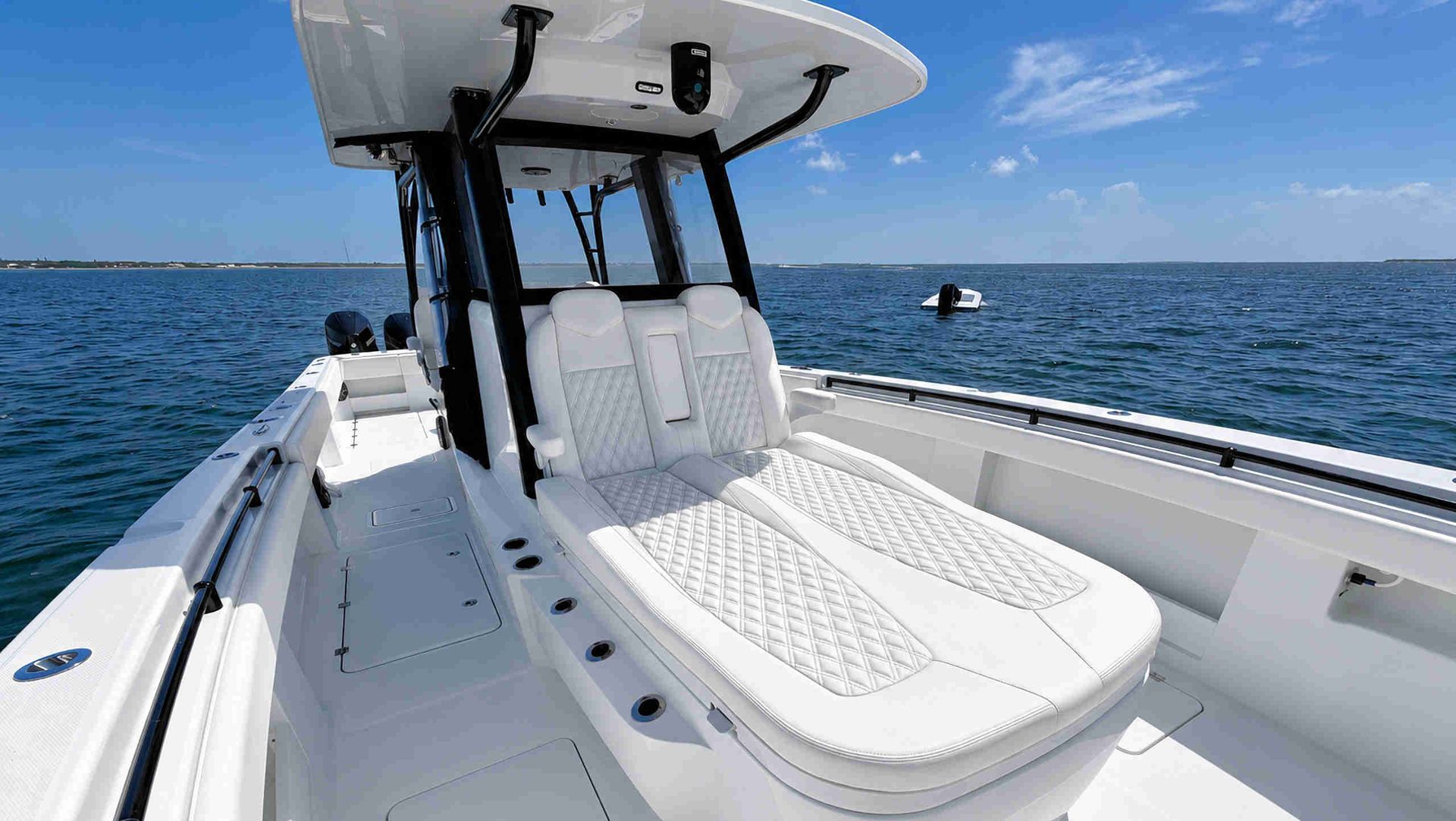 White boat deck seating forward of center console on open blue water under a clear sky.