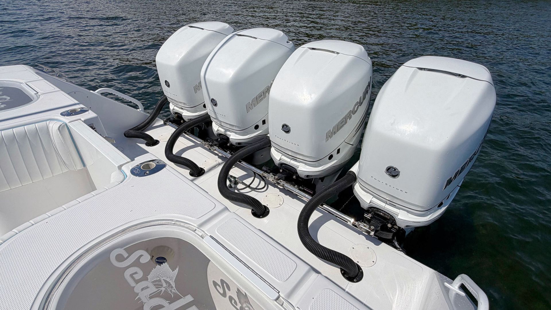 Four white outboard boat engines mounted on a stern over open water