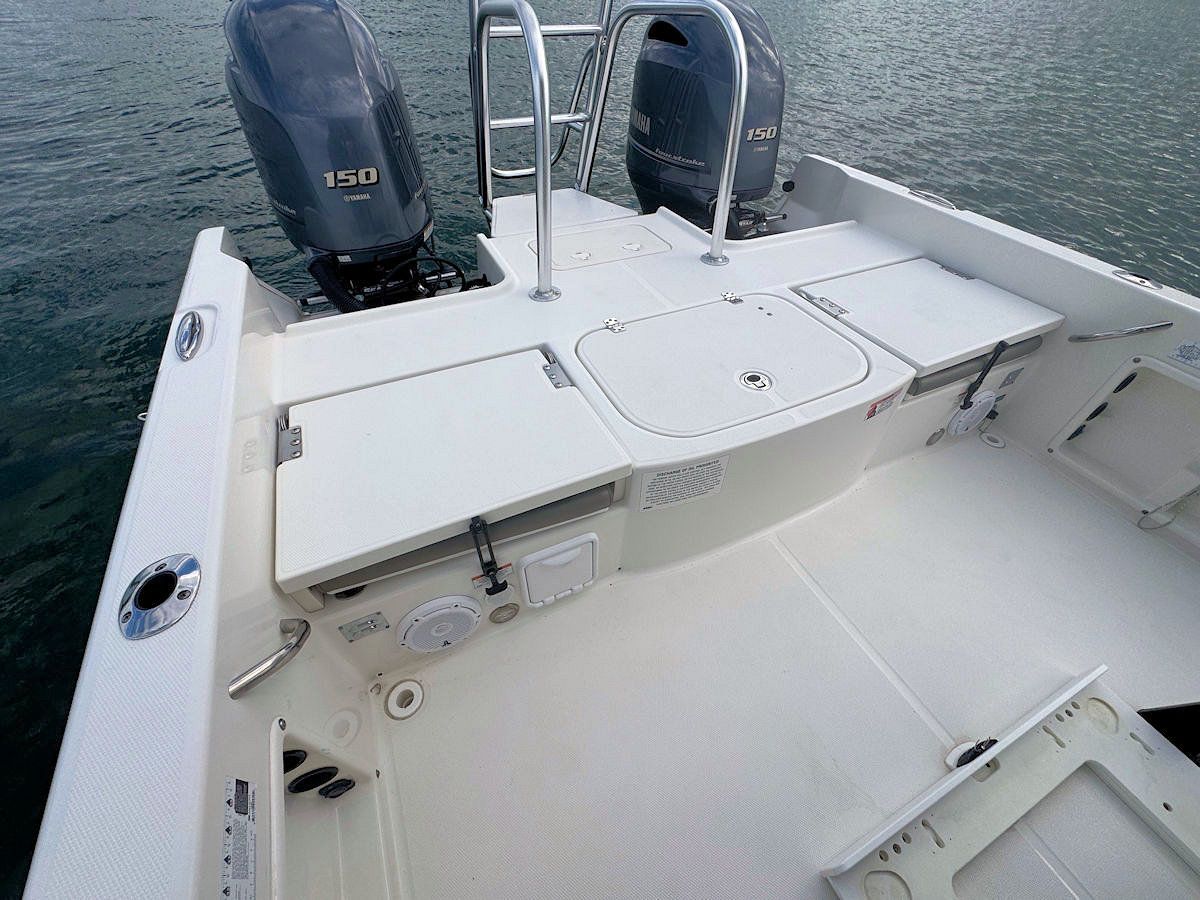 Rear view of a white motorboat with dual outboard engines, a rear platform, and a stainless steel grab rail.