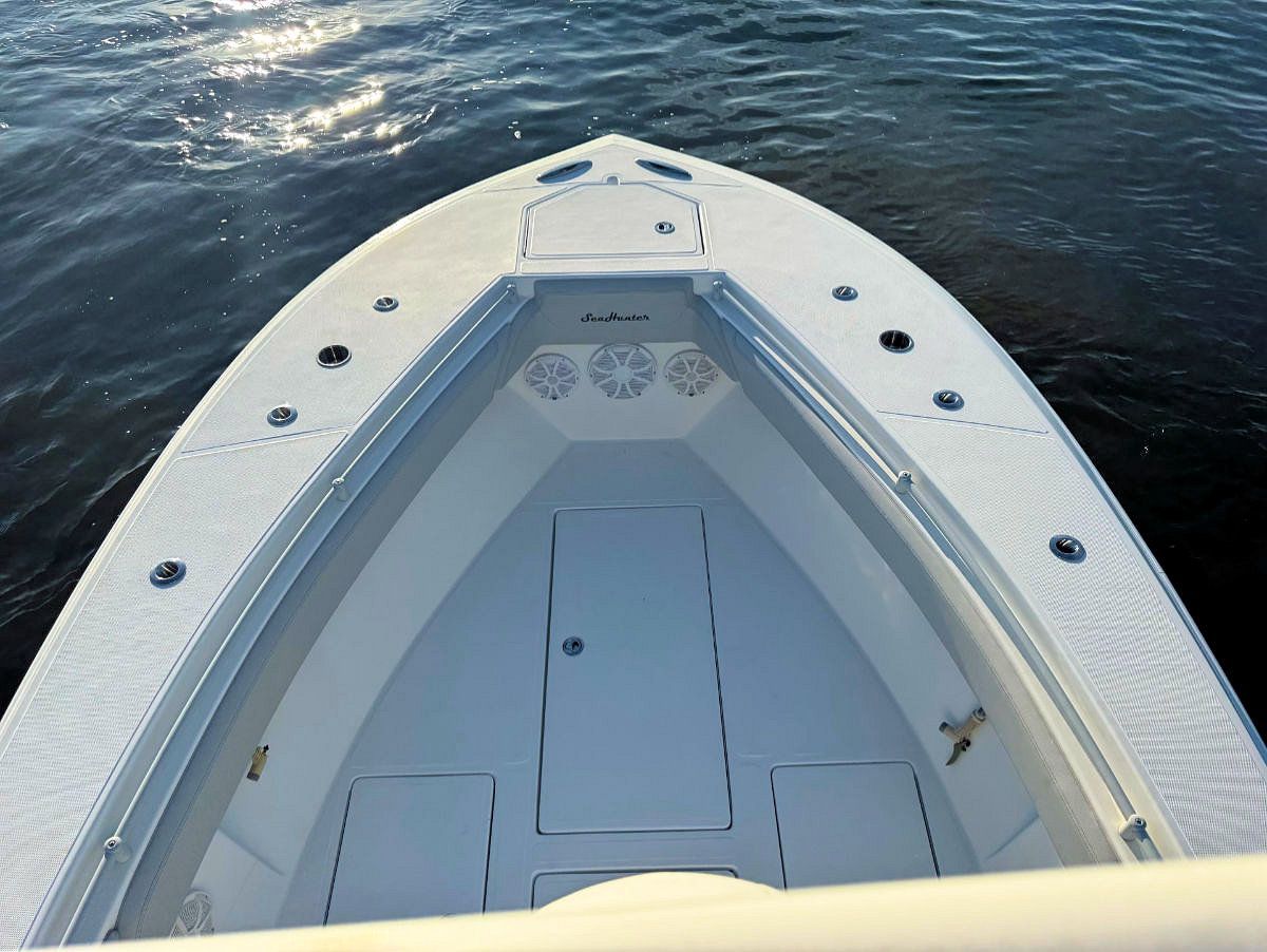 View from the bow of a white fishing boat on the water, with storage compartments visible.