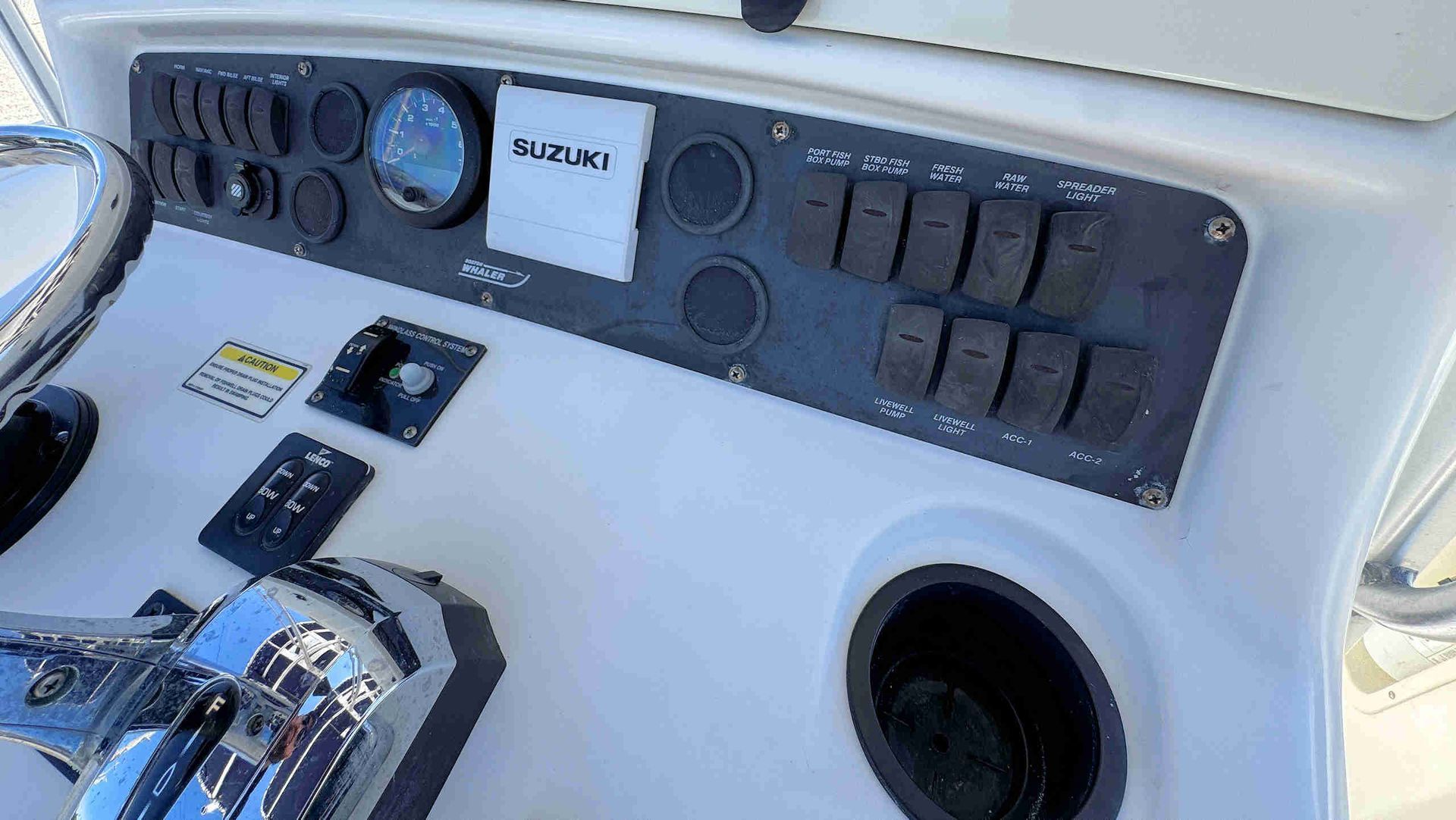 Boat helm console with gauges, switches, and steering wheel panel in white and black.