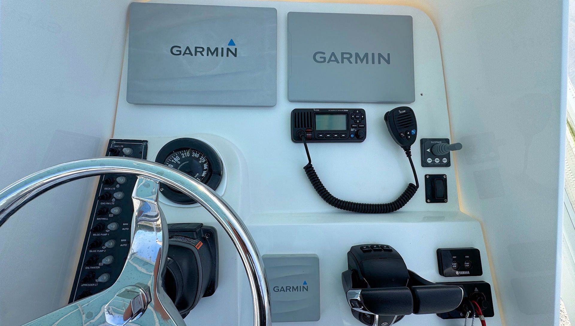 Garmin boat helm dashboard with steering wheel, gauges, GPS display, and controls mounted on a white panel