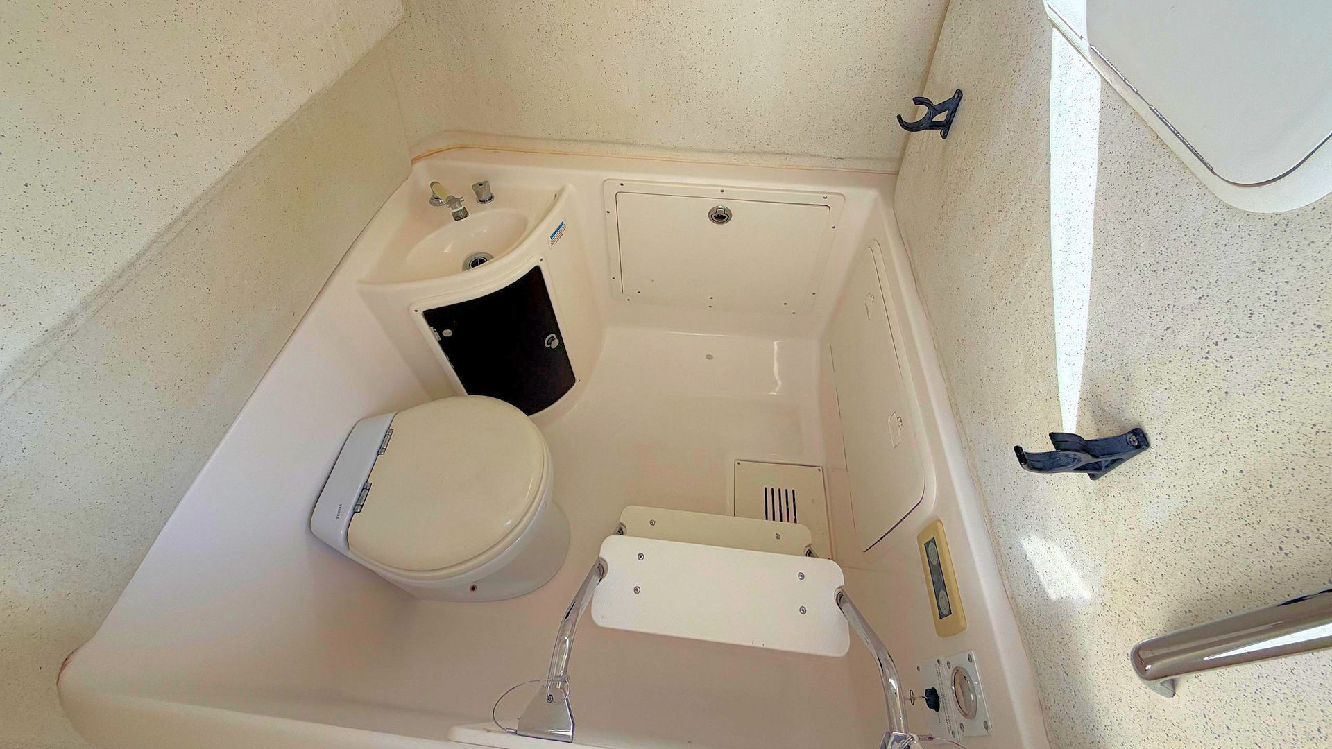 Small bathroom with toilet, sink, and shower/tub in a narrow, beige space.