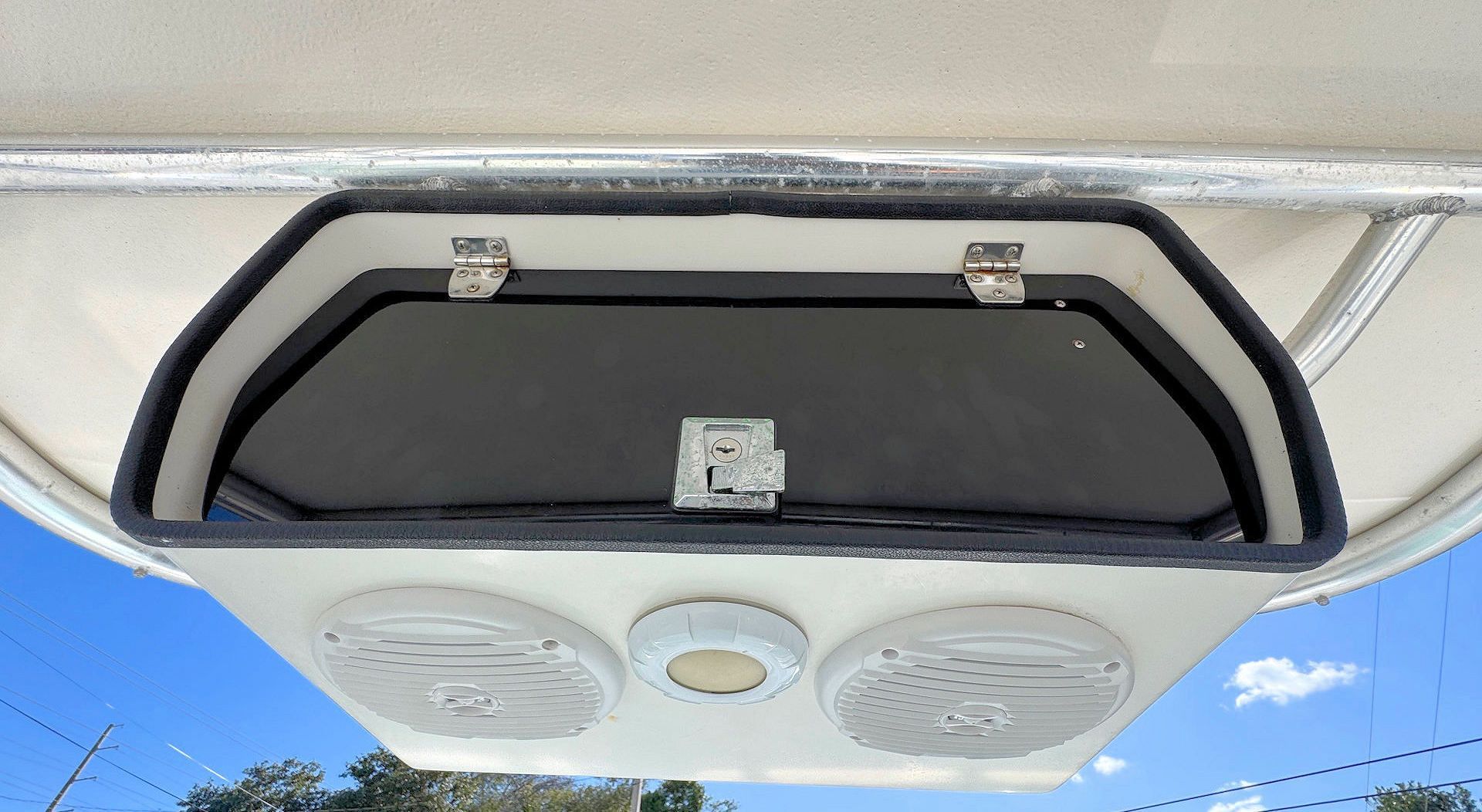 An overhead marine electronics box mounted under a boat canopy, featuring a storage compartment, two speakers, and a light.