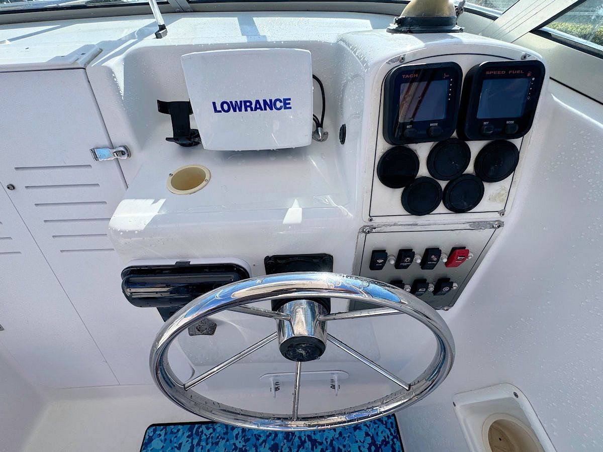 Boat dashboard with steering wheel, gauges, and a Lowrance fish finder.