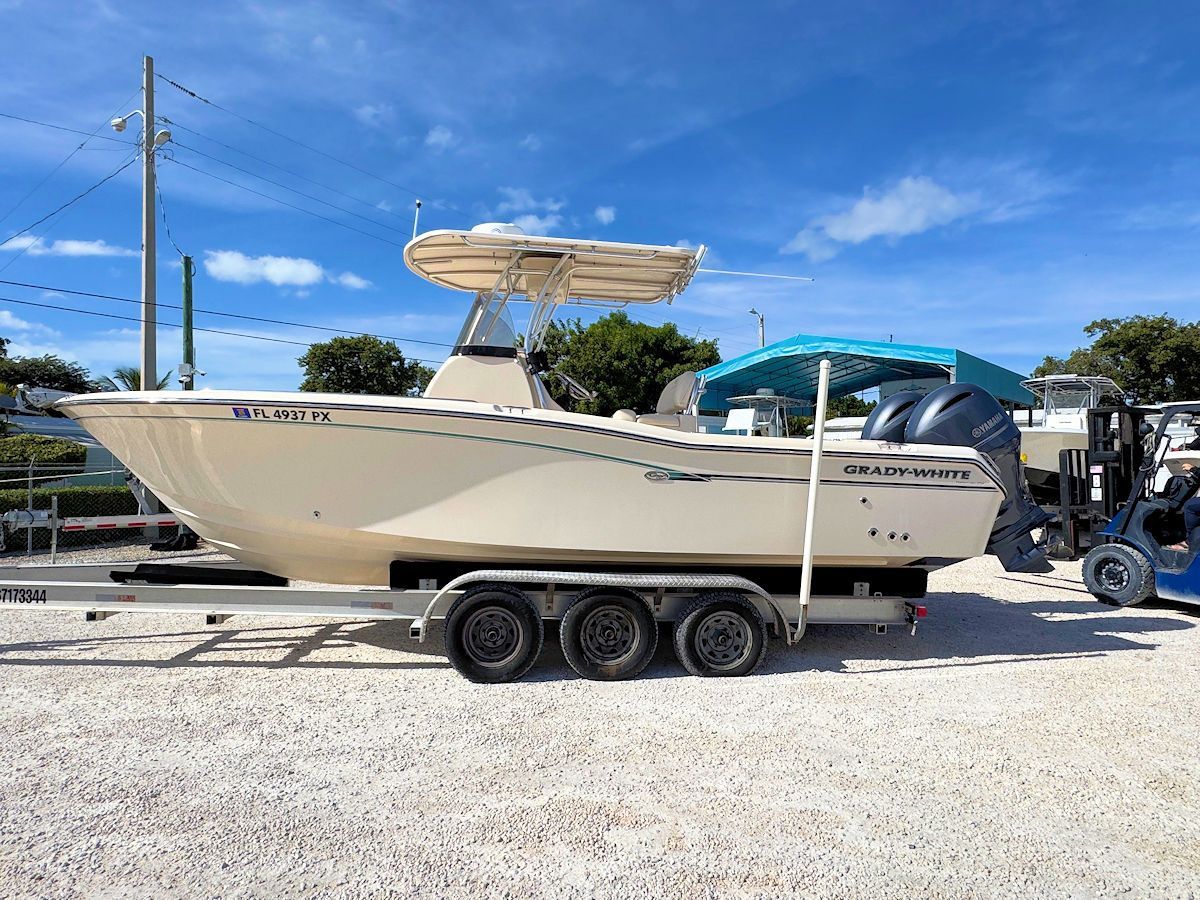 Cream-colored fishing boat on a trailer, under a bright blue sky.