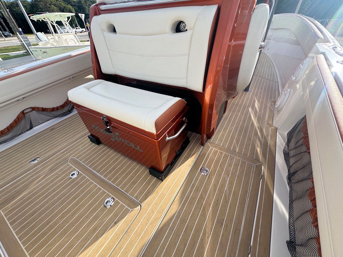 Wooden-decked boat interior with brown and white accents, featuring a cooler and seating.
