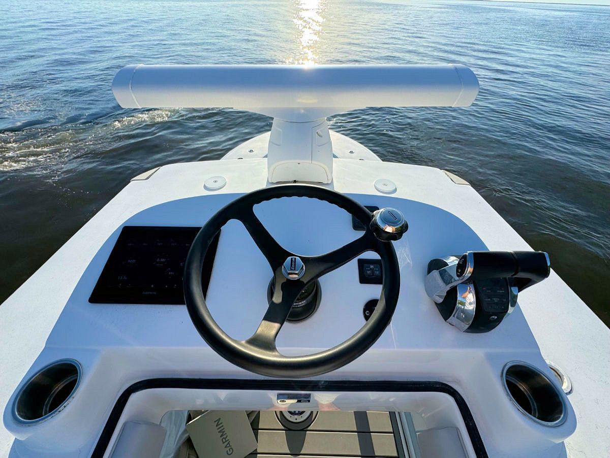 Boat dashboard with steering wheel, radar, and throttle.