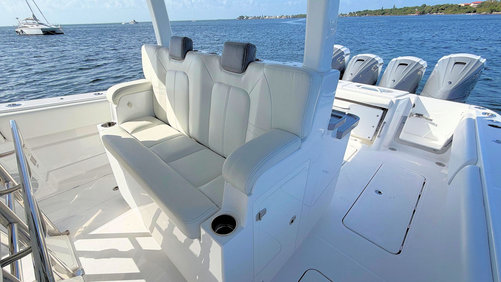 White boat seating area with cushioned bench and deck chairs overlooking the water