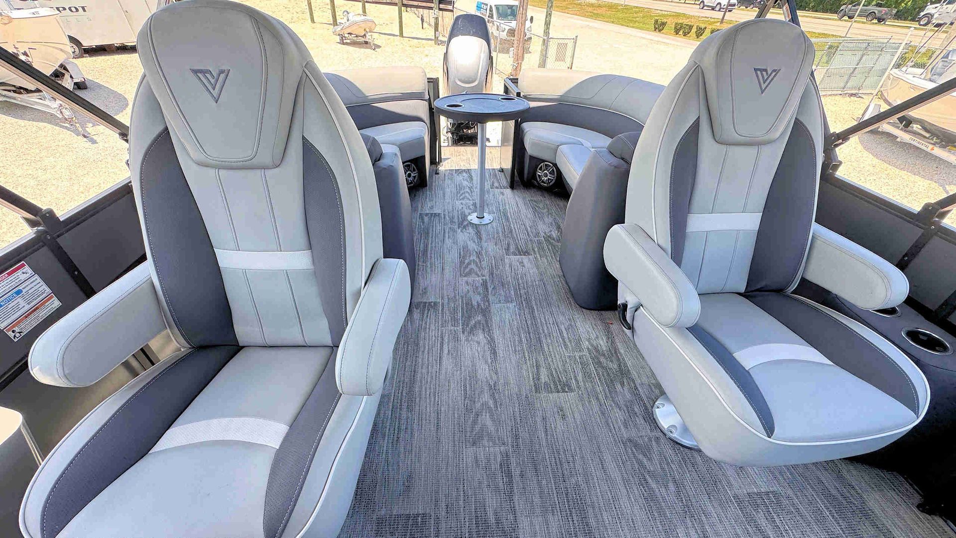 Boat cockpit with two gray captain’s chairs and a textured floor, facing the helm and water ahead