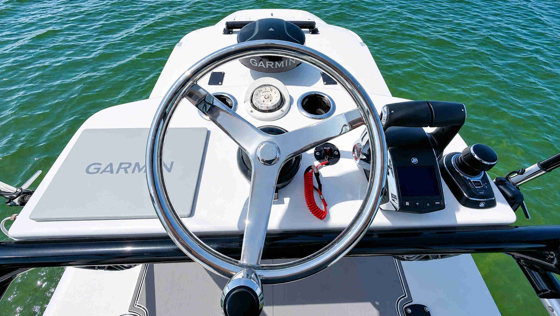 Upper helm including steering wheel and dashboard with green water visible ahead