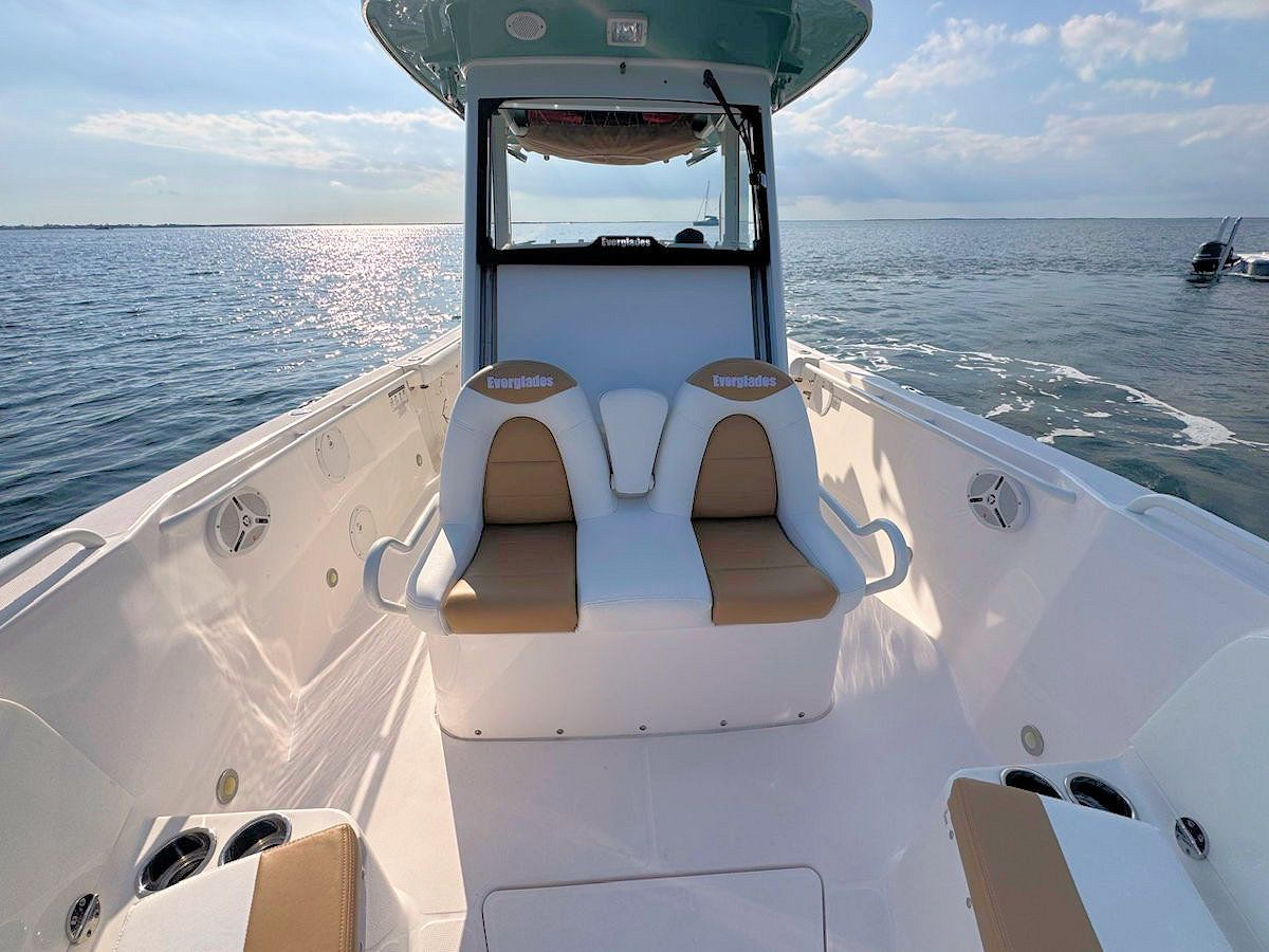 View from inside a white motorboat, out on the water. Beige seats, blue sky, and a bright sunny day.
