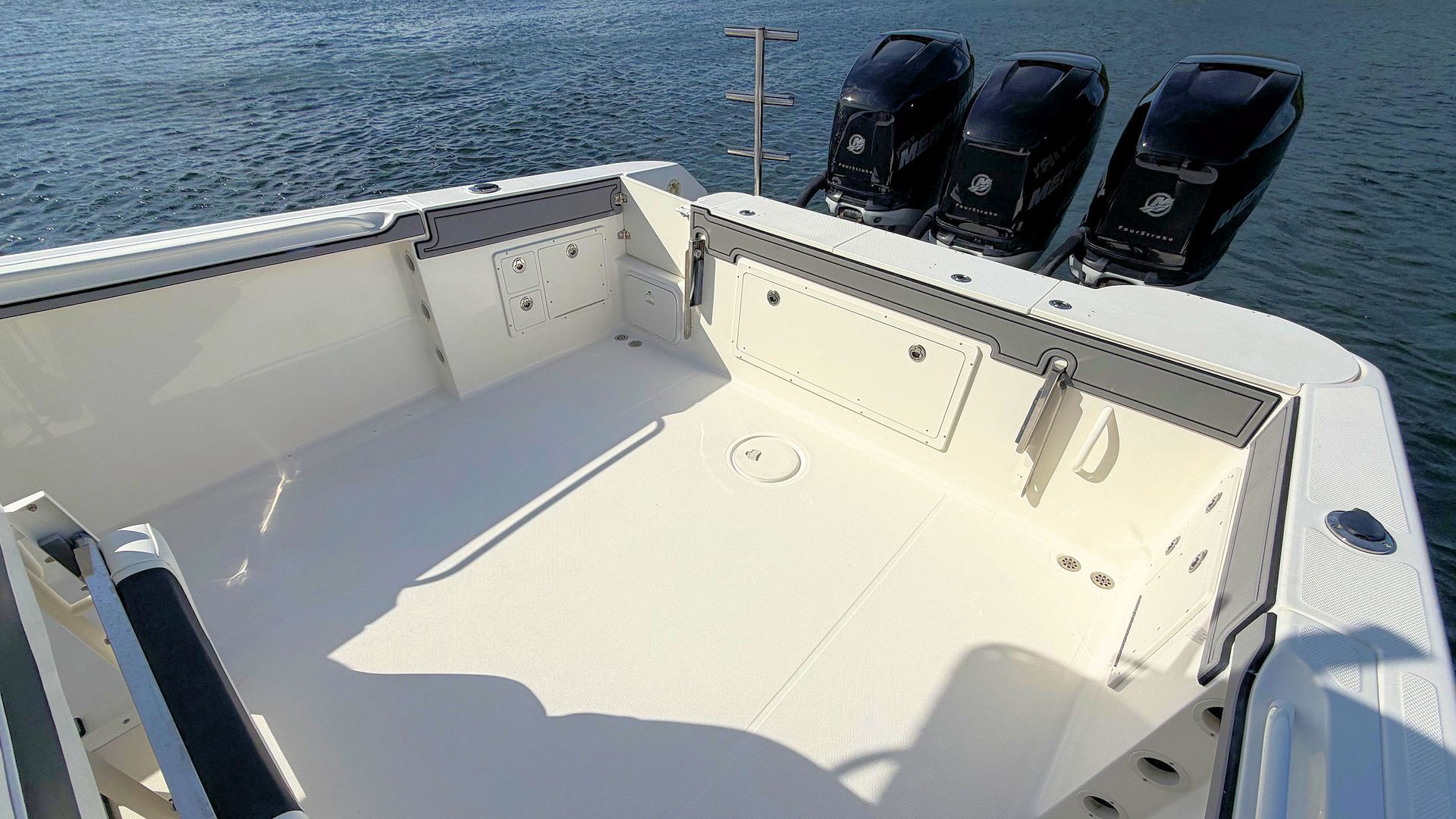 Empty Wellcraft center console boat deck with three outboard motors on the stern, floating on calm water