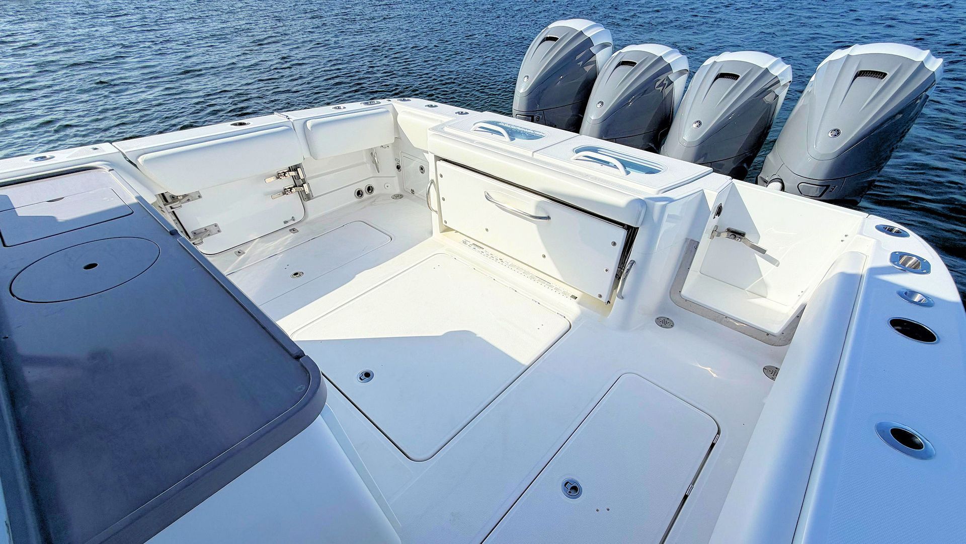 White boat cockpit with cushioned seating and multiple outboard engines on open water