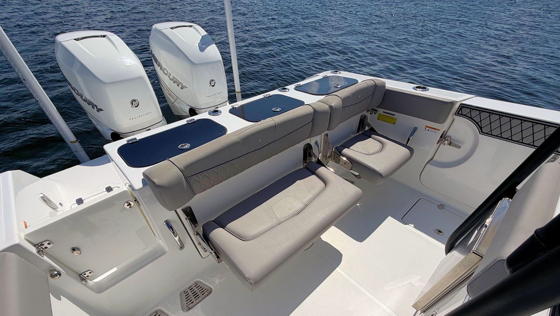 White boat cockpit with gray seats, blue cushions, and twin outboard motors on the water