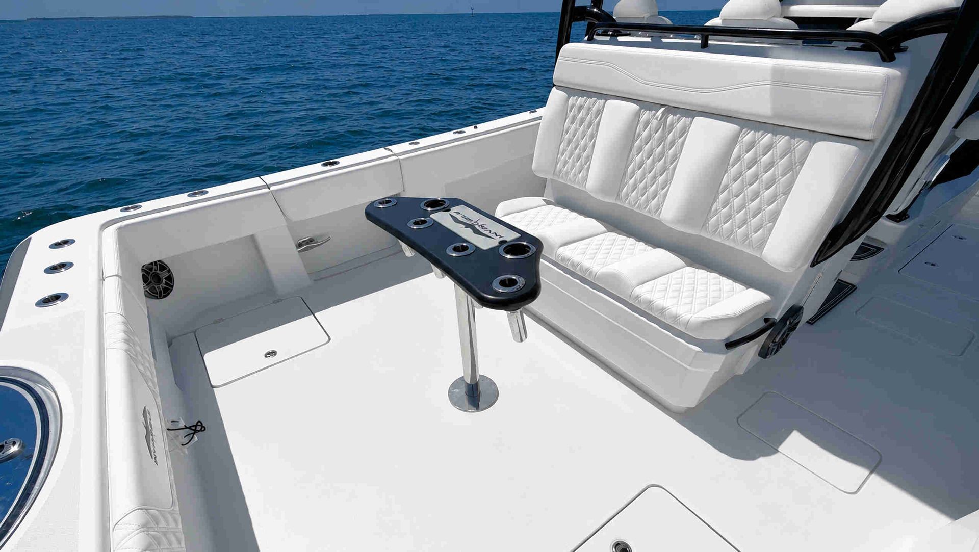 White boat seating area on a yacht deck beside blue ocean water