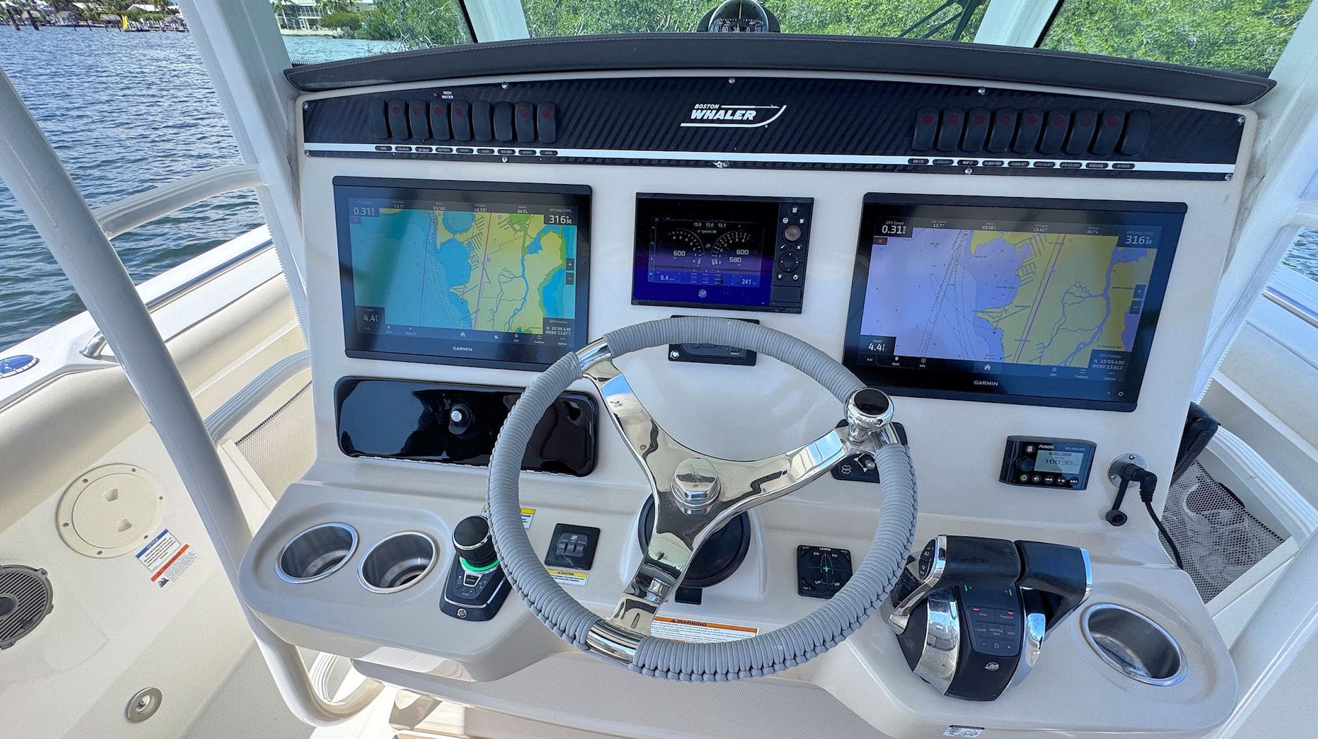 Boat helm with steering wheel, digital displays, and navigation controls in the cockpit