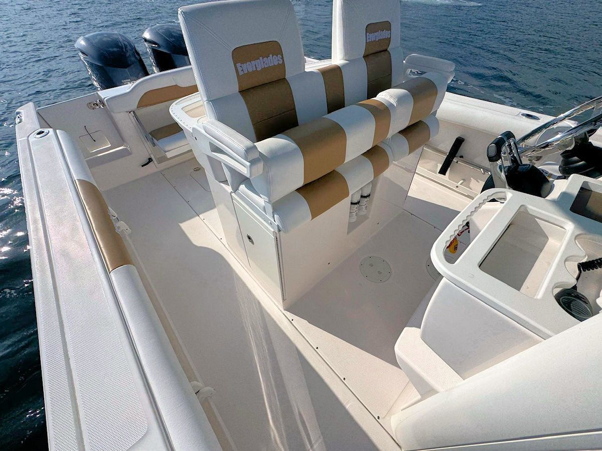 White and tan boat deck interior with cushioned seats and steering wheel.
