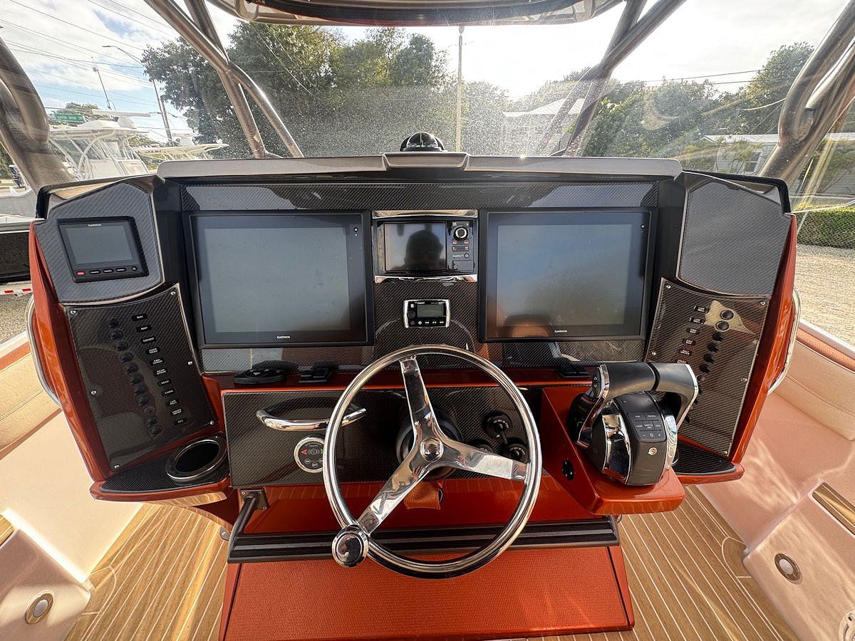 Boat dashboard with two large screens, steering wheel, and controls.