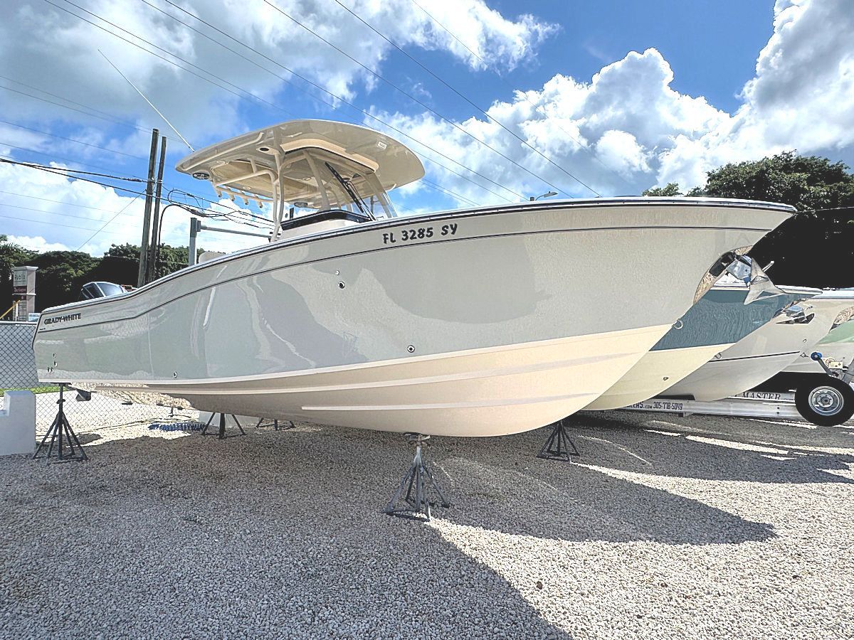 White boat on a gravel surface under a partly cloudy sky.