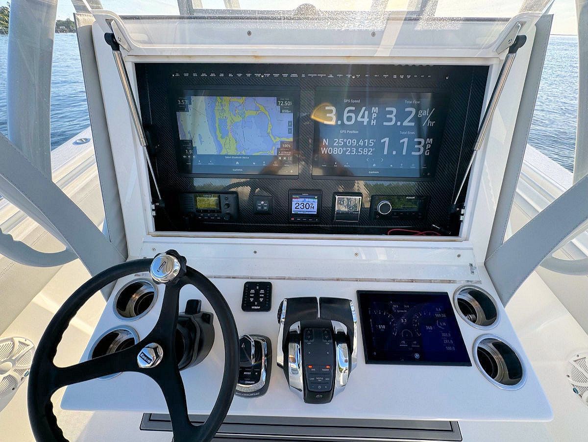 Boat dashboard with steering wheel, navigation display, and control panel.