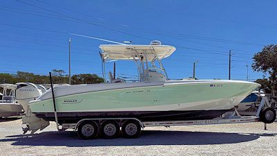 A green and white boat is parked on a trailer.
