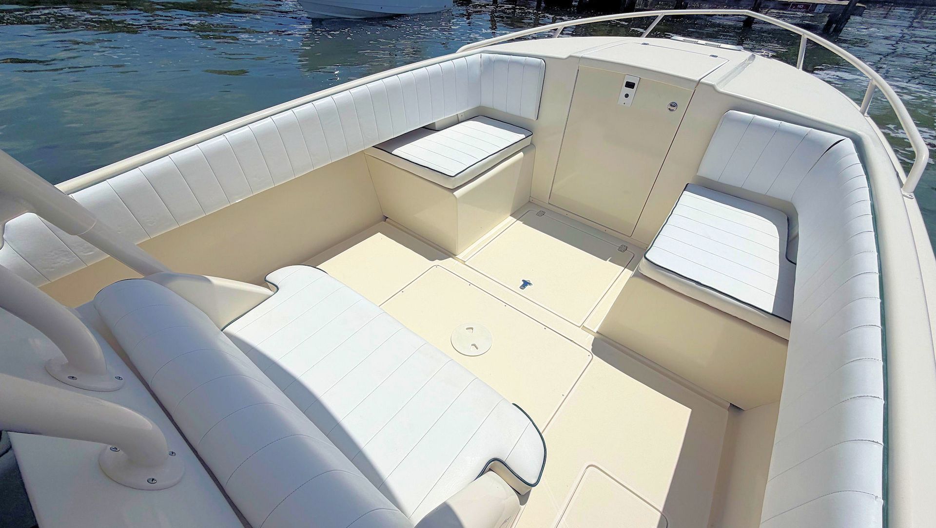 Cream-colored boat bow seats on each side of cuddy access with blue water in the background