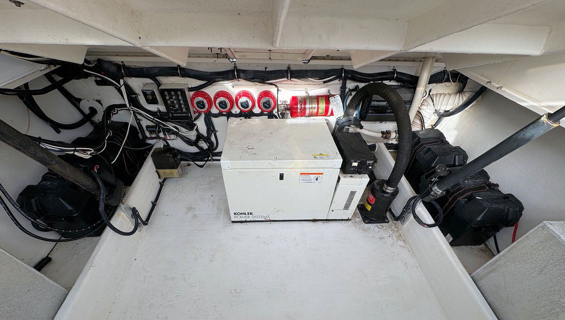 Boat engine compartment with a central white panel, red fittings, and hoses on both sides