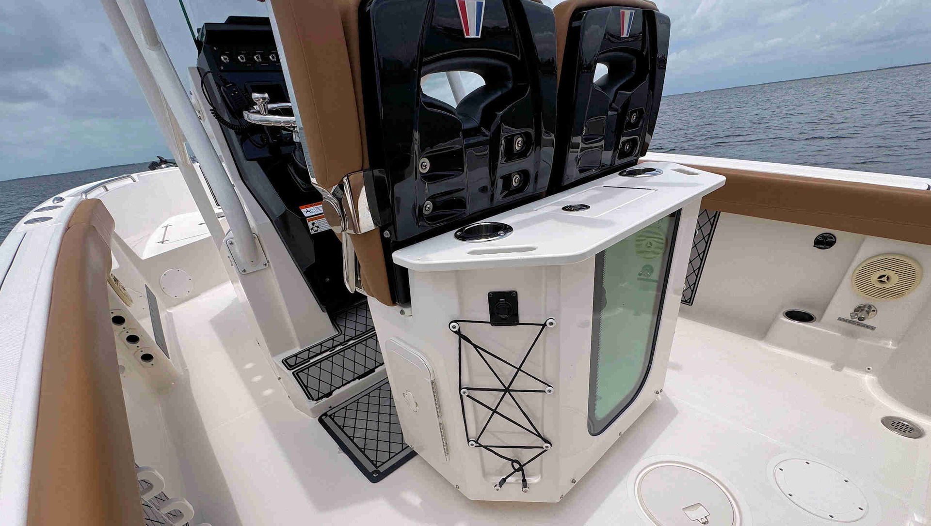 Boat cockpit with helm controls and white seating on open water, seen from the stern